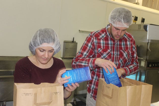 Two employees packing macaroni and cheese boxes into bags