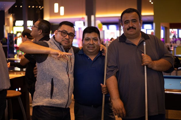 Three men posing with pool sticks at 30th anniversary party