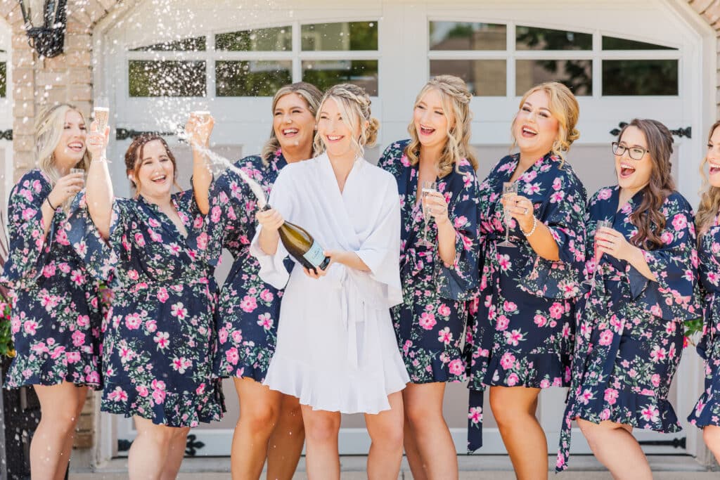 bride with bridesmaids popping champagne