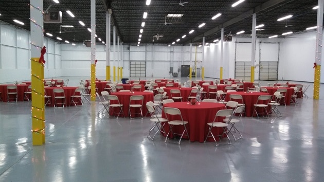 round tables with red tablecloths set up in a warehouse