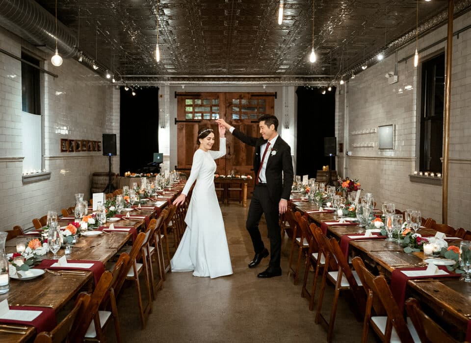 Wedding couple dancing between reception tables