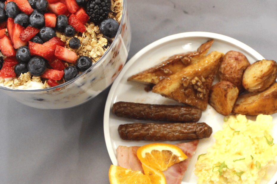 breakfast meal with eggs breakfast meat and yogurt parfait