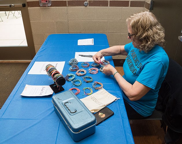 Volunteer arranging bracelets for sale on a table