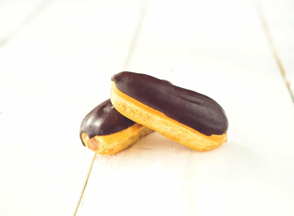 Two mini eclairs on light wood background