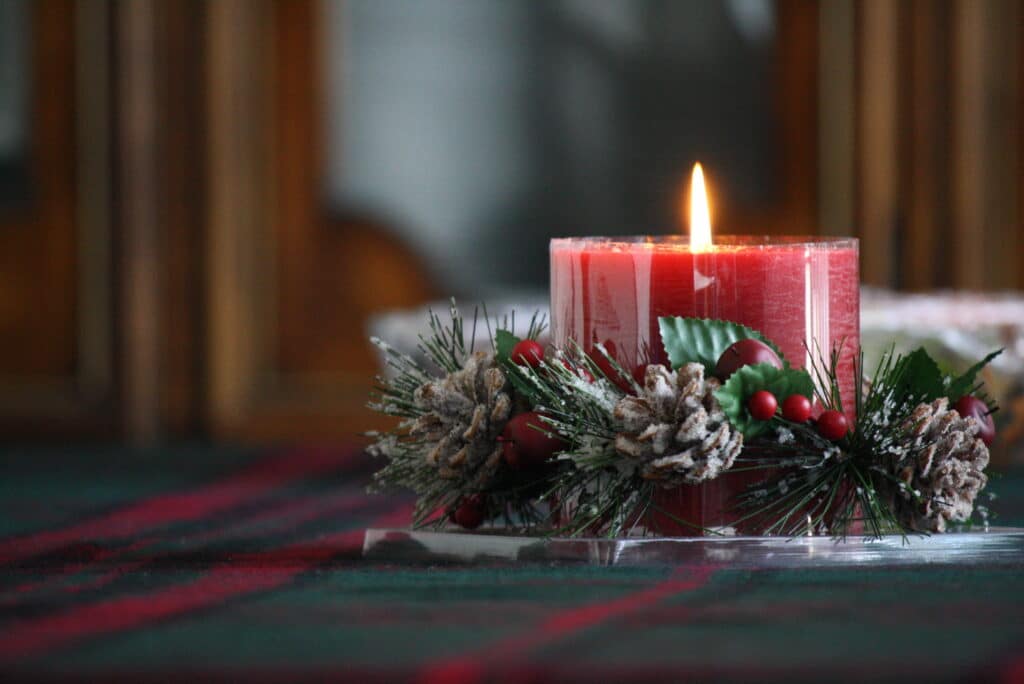 red holiday candle with pinecone decor
